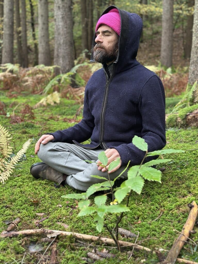 Sascha Delberg tief in Meditation am Moosplatzerl im Wald in unmittelbarer Umgebung des Weltenhofes